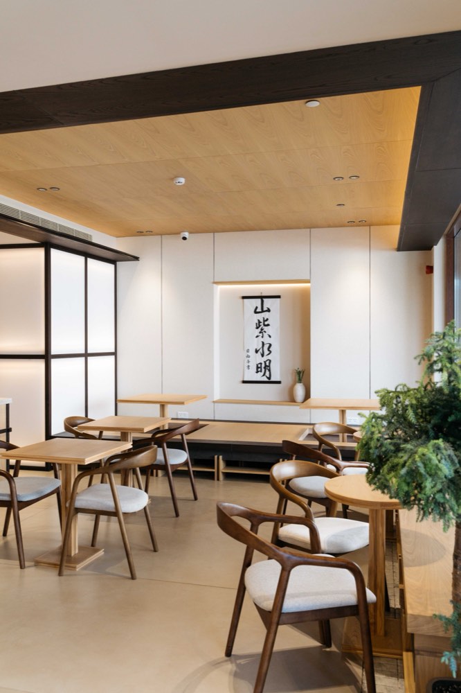 Dining room in pale oak beneath a timber-lined ceiling